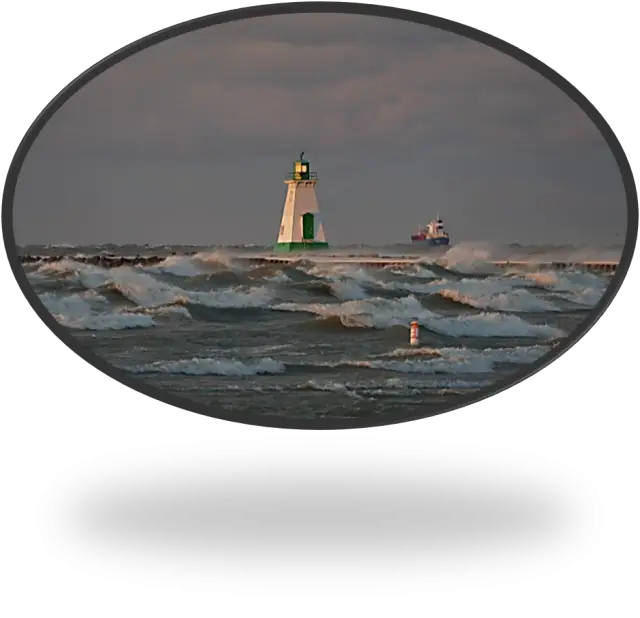 Stormy Lake Ontario as seen from the shore with a lighthouse and freighter in the distance.