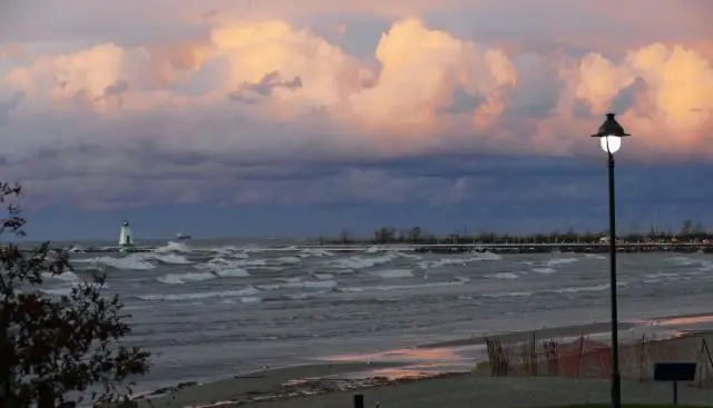 A photo of a stormy Lake Ontario with a small lighthouse and big clouds in the sky.