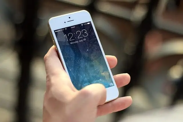 An iphone in a woman's hand with the screen displaying all the apps.
