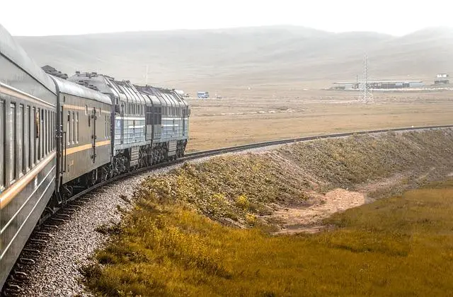 Looking along the side of train enroute across a bleak landscape.