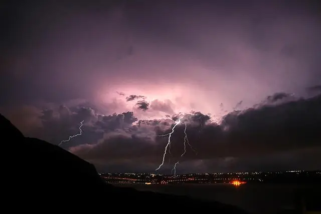 Dark clouds with lightning over a city at night.