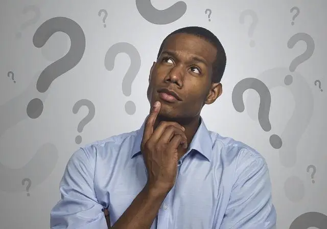 A man looking up and to his right with a finger on his chin thinking.