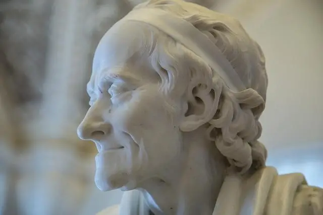 A close-up of a white marble statue of Voltaire.