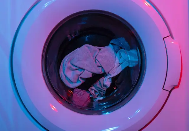 A front loading washing machine with clothes inside mid-cycle.
