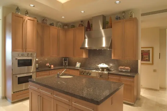 A spotless open-concept kitchen in brown, natural tones with stainless steel appliances.