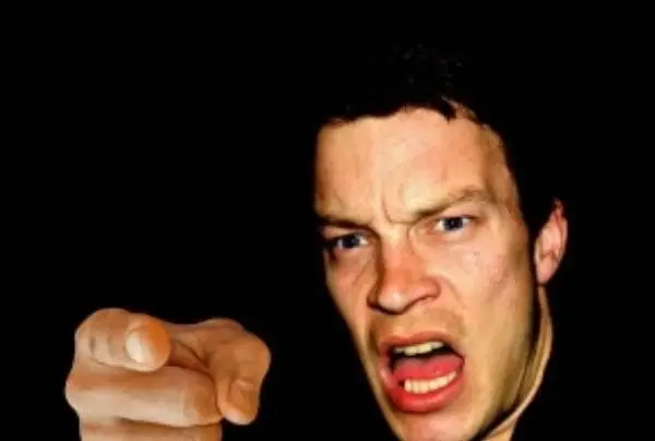 An angry white man pointing his finger and yelling. Background is only black.