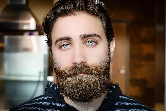 Man with full beard and moustache, not smiling, looking directly at us.