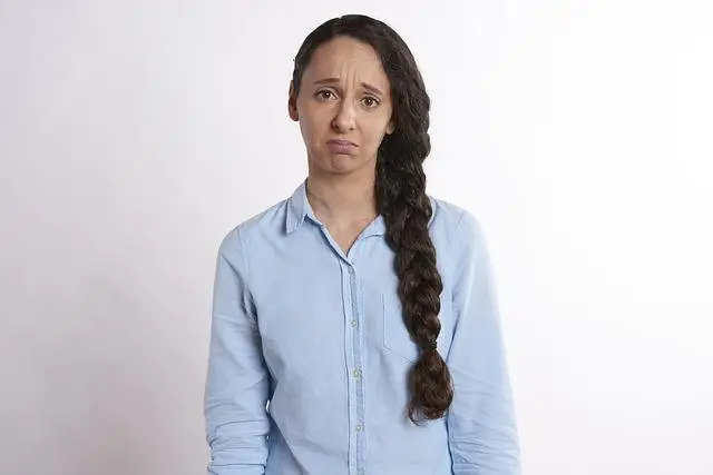 A woman with a blue shirt and a long braid looking very sad.