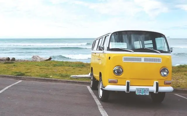 A yellow Volkswagen toaster parked near the ocean.