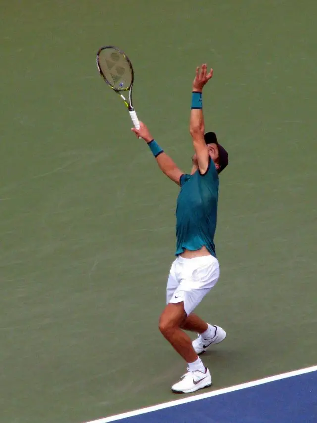 A tennis player throwing the ball in the air ready for a whopping serve.