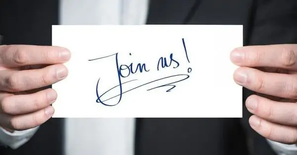 Two male hands holding a card that reads, "Join us!"