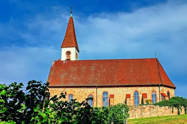 A moderate sized church building, with yellow brick walls, a red roof and a blue sky with wispy clouds.