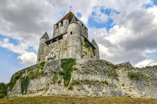 Looking up towards an overgrown stone wall and an old stone monestary.